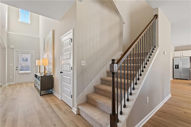 stairway with wood-type flooring and a high ceiling