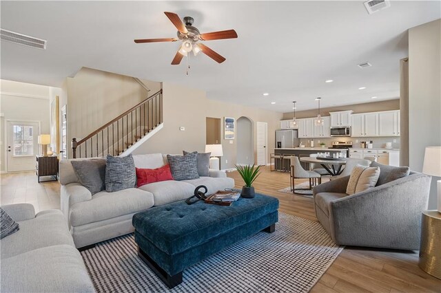 living room with light wood-type flooring and ceiling fan