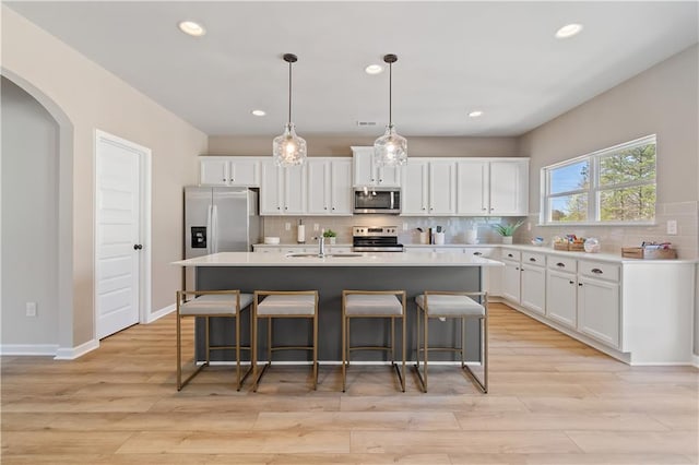 kitchen with white cabinets, a kitchen island with sink, and stainless steel appliances