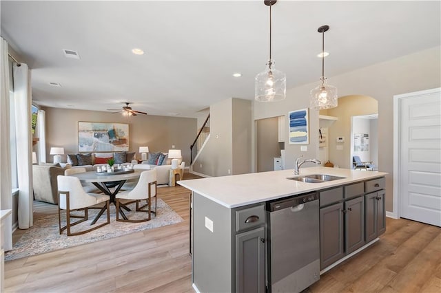 kitchen featuring stainless steel dishwasher, a center island with sink, light wood-type flooring, and ceiling fan