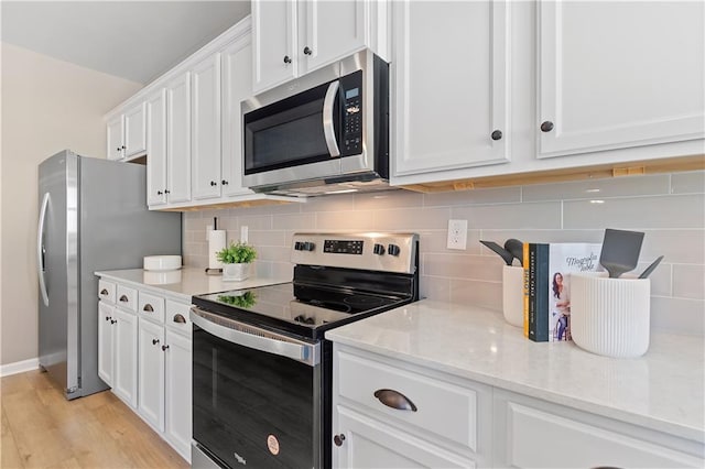 kitchen featuring white cabinets, backsplash, appliances with stainless steel finishes, light stone countertops, and light hardwood / wood-style floors