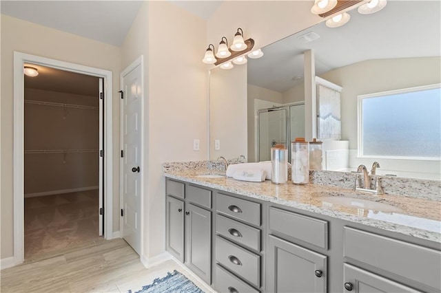 bathroom featuring a shower with door, vanity, wood-type flooring, and vaulted ceiling