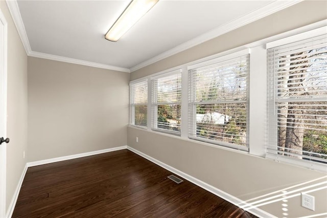 spare room featuring visible vents, plenty of natural light, ornamental molding, and dark wood-style flooring