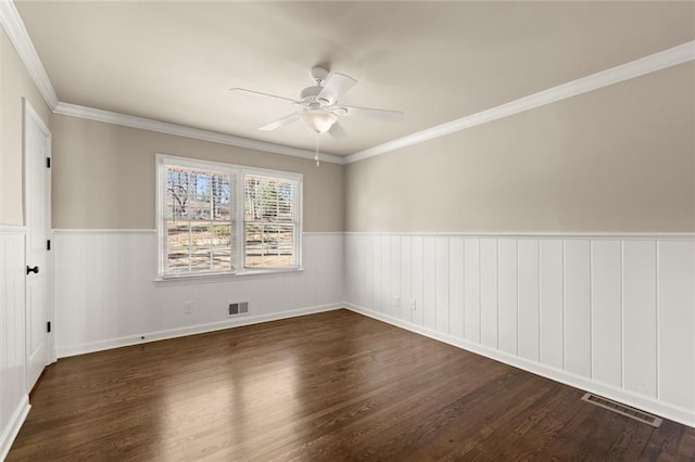 spare room with visible vents, a wainscoted wall, wood finished floors, and a ceiling fan