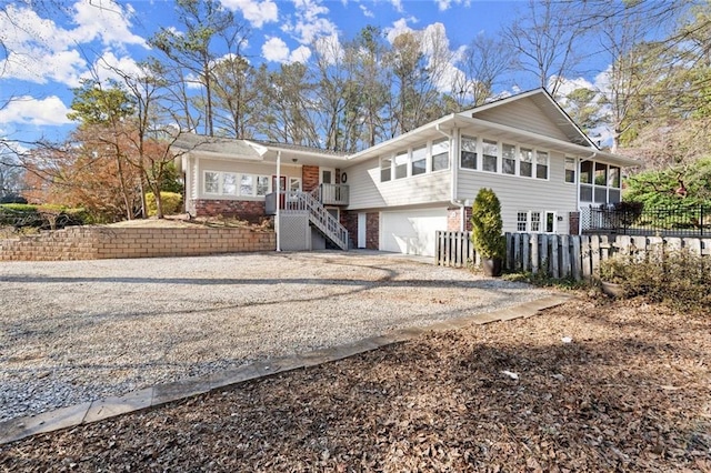 single story home with stairway, fence, driveway, an attached garage, and brick siding