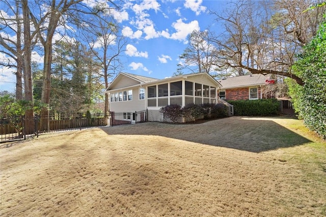 view of front of house featuring a front lawn, fence, brick siding, and a sunroom