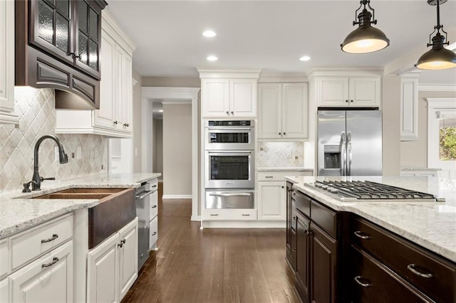 kitchen with dark brown cabinets, appliances with stainless steel finishes, dark wood-style floors, white cabinets, and a warming drawer