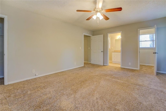 unfurnished bedroom with light carpet, a walk in closet, ensuite bath, ceiling fan, and a closet