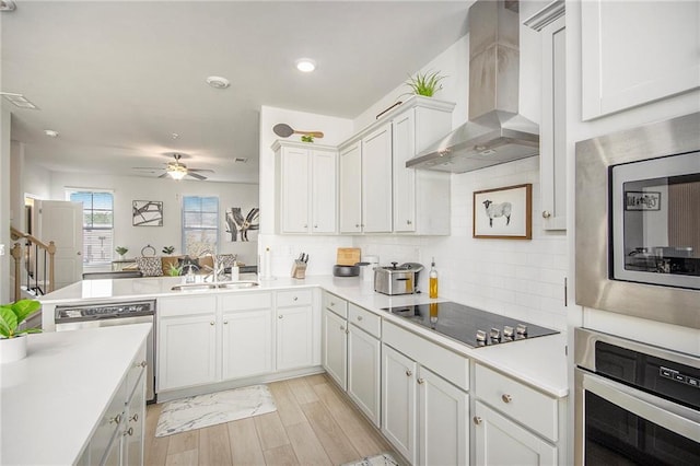 110 Cobalt Dr, Fayetteville, GA 30214 - kitchen featuring appliances with stainless steel finishes, sink, white cabinets, kitchen peninsula, and wall chimney range hood