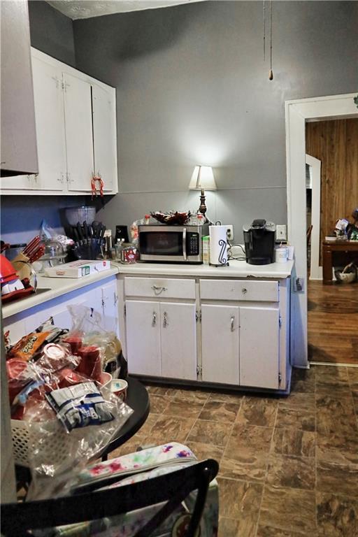 405 Pennington Ave SW, Rome, GA 30161 - kitchen with stone finish flooring, stainless steel microwave, light countertops, and white cabinets