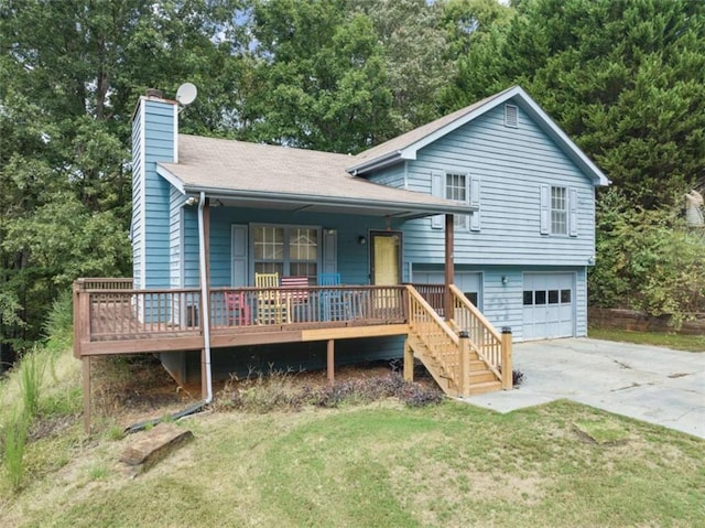 tri-level home with covered porch, concrete driveway, a front yard, an attached garage, and a chimney