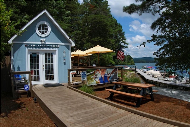 exterior space with french doors, a water view, and an outdoor structure