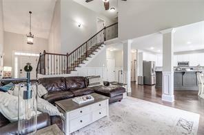 living room featuring decorative columns, a high ceiling, and stairway