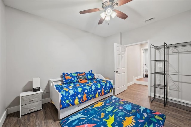 bedroom with ceiling fan, wood finished floors, visible vents, and baseboards