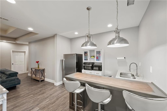 kitchen with visible vents, dark wood finished floors, a peninsula, freestanding refrigerator, and a sink