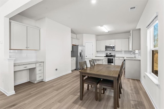 dining room featuring sink, built in desk, and light hardwood / wood-style floors