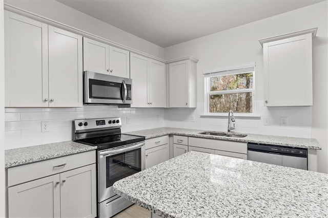 kitchen with appliances with stainless steel finishes, sink, white cabinets, and decorative backsplash