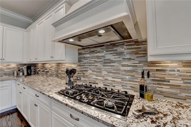 kitchen featuring premium range hood, white cabinetry, tasteful backsplash, light stone countertops, and stainless steel gas stovetop