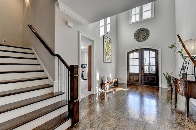 foyer featuring a towering ceiling, ornamental molding, and french doors