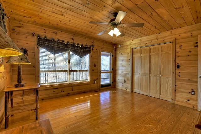 interior space featuring hardwood / wood-style floors, ceiling fan, wood ceiling, and wooden walls