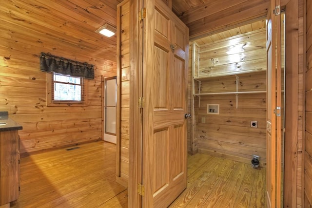 hallway featuring wood walls, light hardwood / wood-style floors, and wooden ceiling