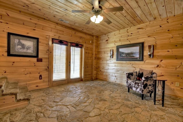 interior space featuring ceiling fan, wooden ceiling, and wooden walls