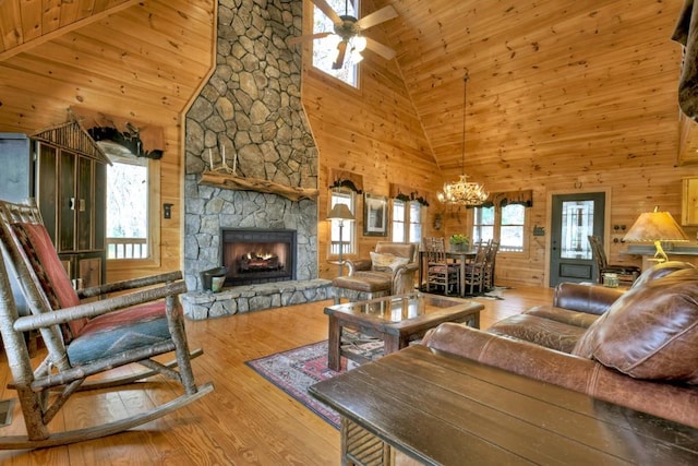 living room featuring light wood-type flooring, high vaulted ceiling, and a stone fireplace