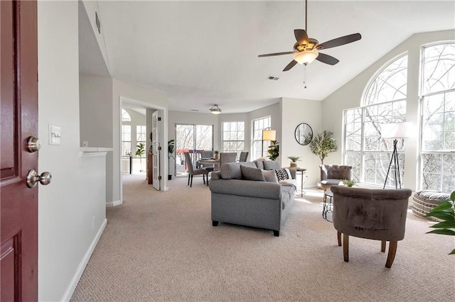 living area featuring visible vents, a ceiling fan, baseboards, light colored carpet, and vaulted ceiling