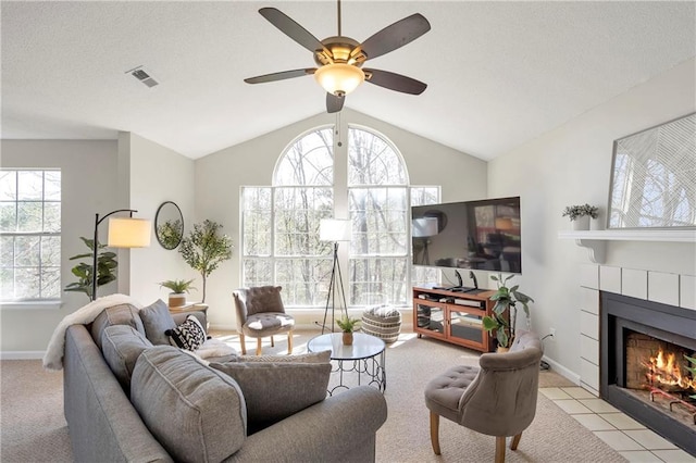 living room featuring visible vents, a tile fireplace, baseboards, and lofted ceiling