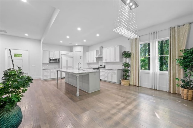 304 Old Cove Rd N, Jasper, GA 30143 - kitchen with appliances with stainless steel finishes, wall chimney exhaust hood, a breakfast bar area, light wood finished floors, and an island with sink