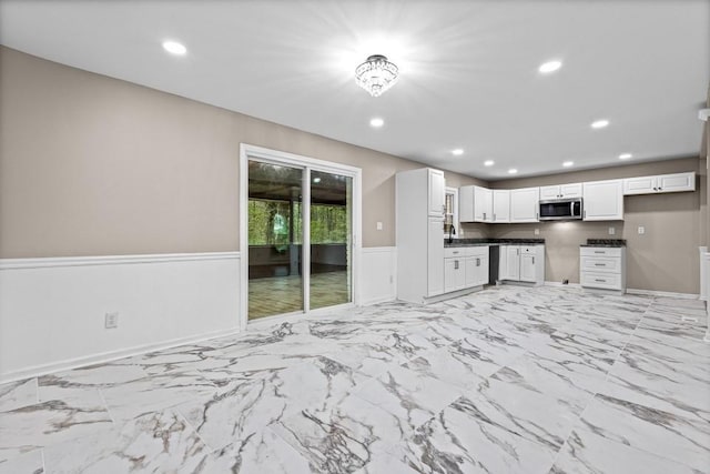 2617 Peggy Sue Ln, Morrow, GA 30260 - kitchen with stainless steel microwave, white cabinetry, wainscoting, recessed lighting, and dark countertops