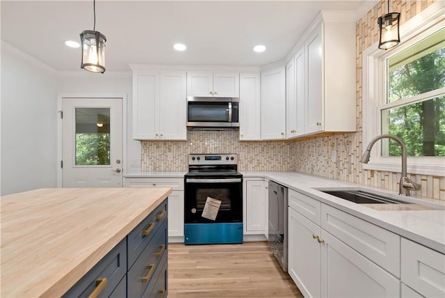 kitchen with sink, appliances with stainless steel finishes, butcher block counters, hanging light fixtures, and white cabinets