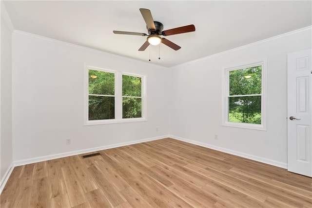 empty room with ornamental molding, a wealth of natural light, and light hardwood / wood-style floors