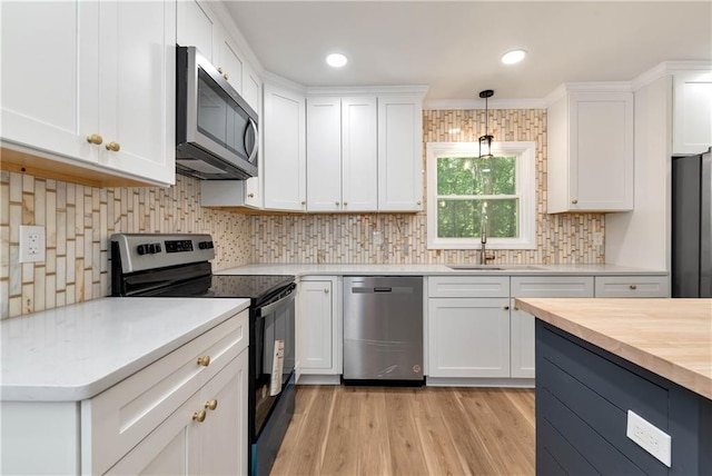 kitchen featuring pendant lighting, butcher block countertops, sink, appliances with stainless steel finishes, and white cabinetry