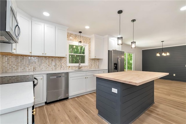 kitchen featuring pendant lighting, white cabinets, a center island, stainless steel appliances, and light wood-type flooring