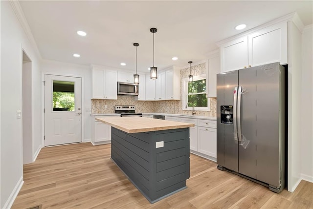 kitchen featuring white cabinetry, hanging light fixtures, stainless steel appliances, and a kitchen island