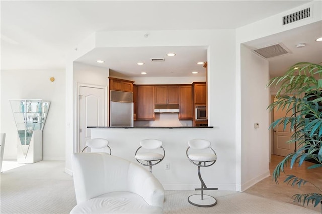 2828 Peachtree Rd NW Unit 2002, Atlanta, GA 30305 - kitchen with built in appliances, under cabinet range hood, brown cabinetry, light carpet, and recessed lighting