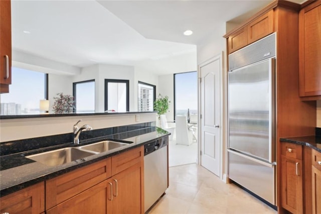 2828 Peachtree Rd NW Unit 2002, Atlanta, GA 30305 - kitchen with appliances with stainless steel finishes, dark stone countertops, brown cabinetry, light tile patterned floors, and recessed lighting