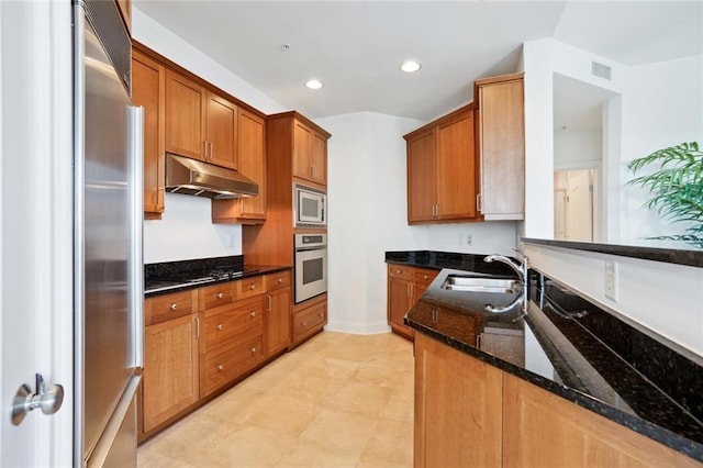 2828 Peachtree Rd NW Unit 2002, Atlanta, GA 30305 - kitchen featuring stainless steel appliances, under cabinet range hood, dark stone countertops, brown cabinetry, and recessed lighting