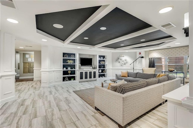 living room featuring beam ceiling, built in features, light hardwood / wood-style floors, and ornate columns