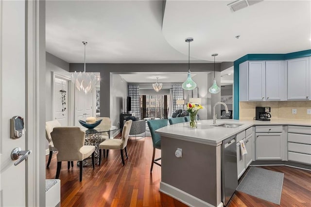 kitchen featuring dark hardwood / wood-style floors, pendant lighting, sink, stainless steel dishwasher, and kitchen peninsula