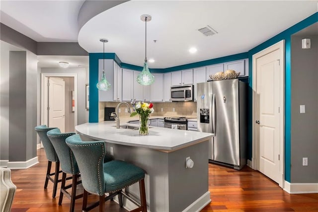 kitchen with pendant lighting, sink, a breakfast bar area, stainless steel appliances, and decorative backsplash