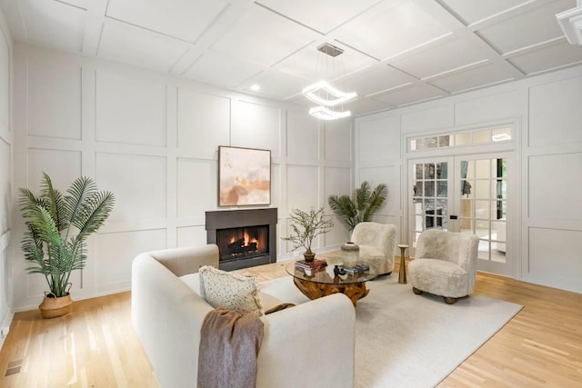 1430 N Harris Rdg, Atlanta, GA 30327 - living room with a decorative wall, light wood finished floors, a warm lit fireplace, a chandelier, and french doors