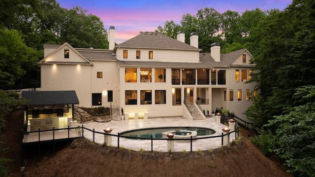 1430 N Harris Rdg, Atlanta, GA 30327 - back of property at dusk featuring stairs, a chimney, a pool with connected hot tub, and a patio