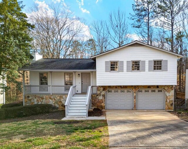 tri-level home with stone siding, a chimney, stairway, and a porch