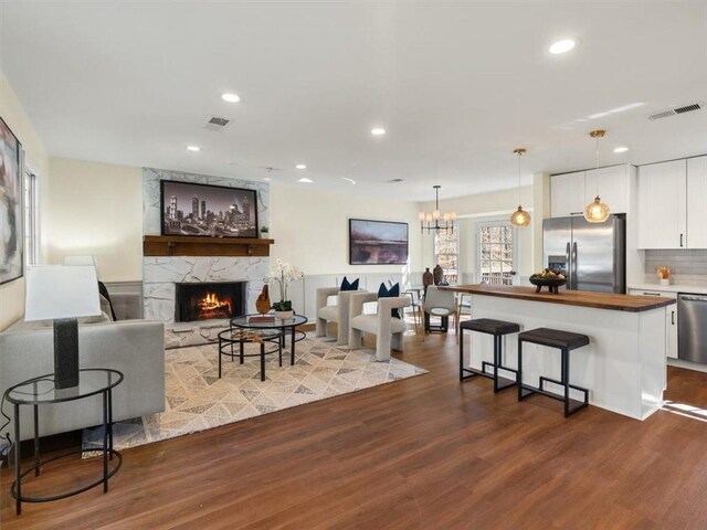 living area featuring a fireplace, dark wood finished floors, visible vents, and recessed lighting