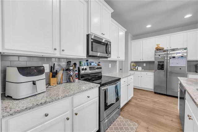 5615 Parkview Ln, Flowery Branch, GA 30542 - kitchen with appliances with stainless steel finishes, white cabinets, tasteful backsplash, light wood-style flooring, and recessed lighting