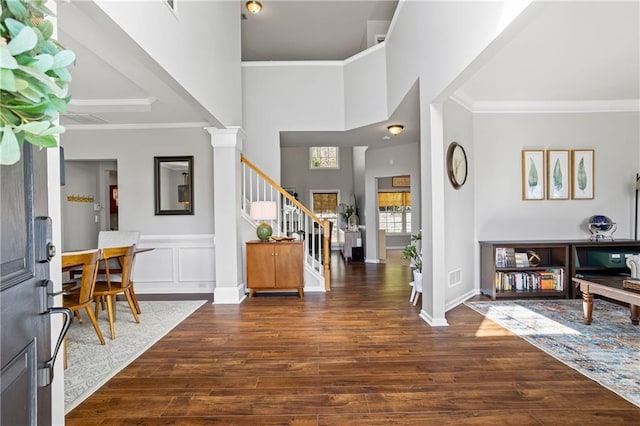 entryway featuring stairs, ornamental molding, wood finished floors, and decorative columns