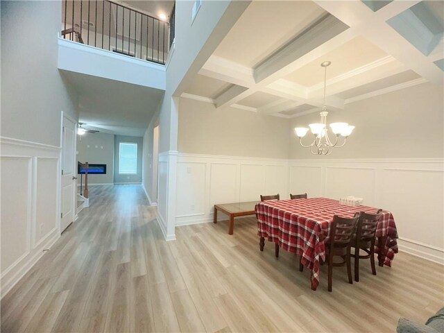 dining space featuring coffered ceiling, ceiling fan with notable chandelier, beamed ceiling, and wood-type flooring