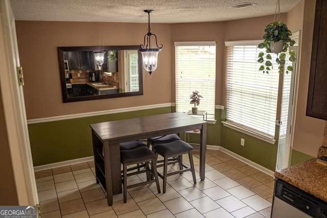 3269 N Winds Trl N, Douglasville, GA 30135 - dining space with a textured ceiling, light tile patterned flooring, baseboards, and a chandelier